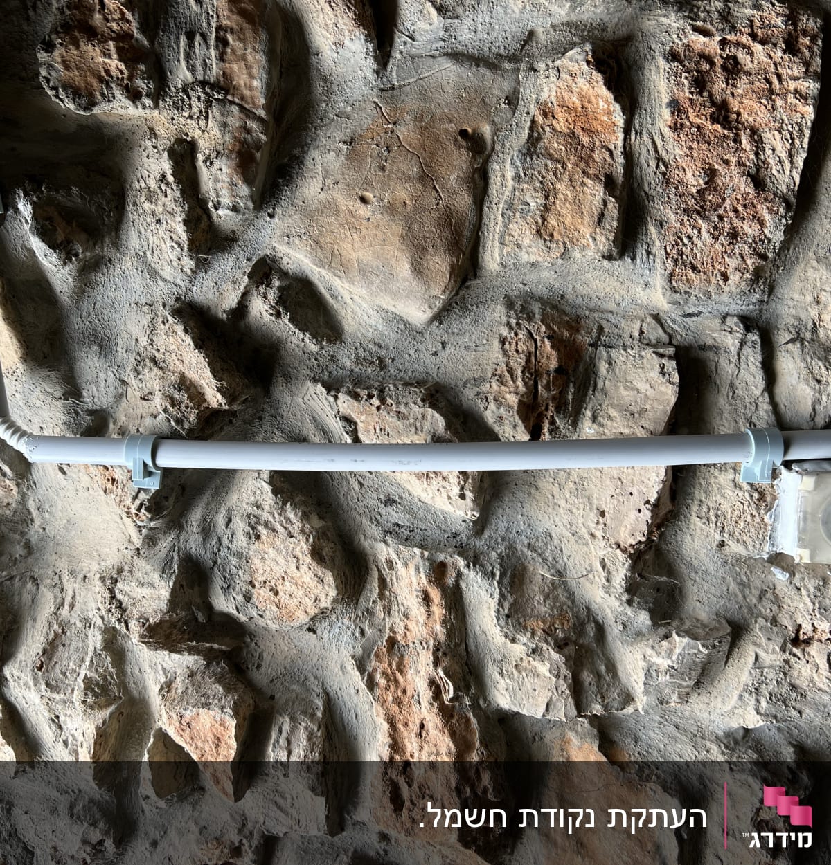 צינור חשמל על קיר אבן עם שקע חשמלי